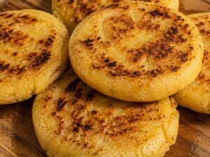 Close-up of freshly made golden corn arepas stacked on a rustic wooden board in Venezuela