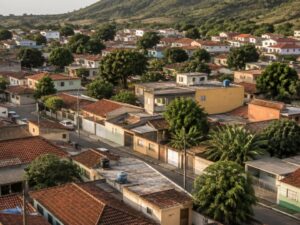 Aerial view of a present-day residential neighborhood with red tile and flat roofs, leafy trees and green hills beyond in Brazil