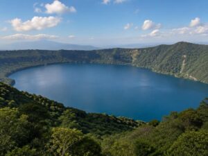 Deep blue crater lake surrounded by steep forested volcanic hills under a clear sky in El Salvador