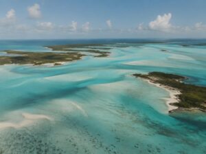 Aerial view of shallow turquoise sandbars winding between low green cays in the Bahamas