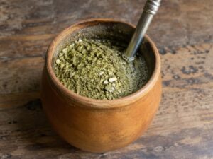 Close-up of a mate gourd filled with yerba mate and a metal bombilla on a rustic wooden table in Argentina