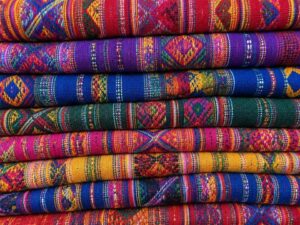 Stacked handwoven textiles with bright geometric patterns in red, purple, blue, green and yellow in Guatemala