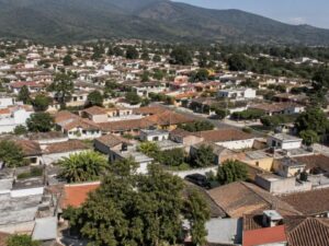 Aerial view of a present-day residential neighborhood with tile and flat roofs, courtyard trees and forested hills in Guatemala